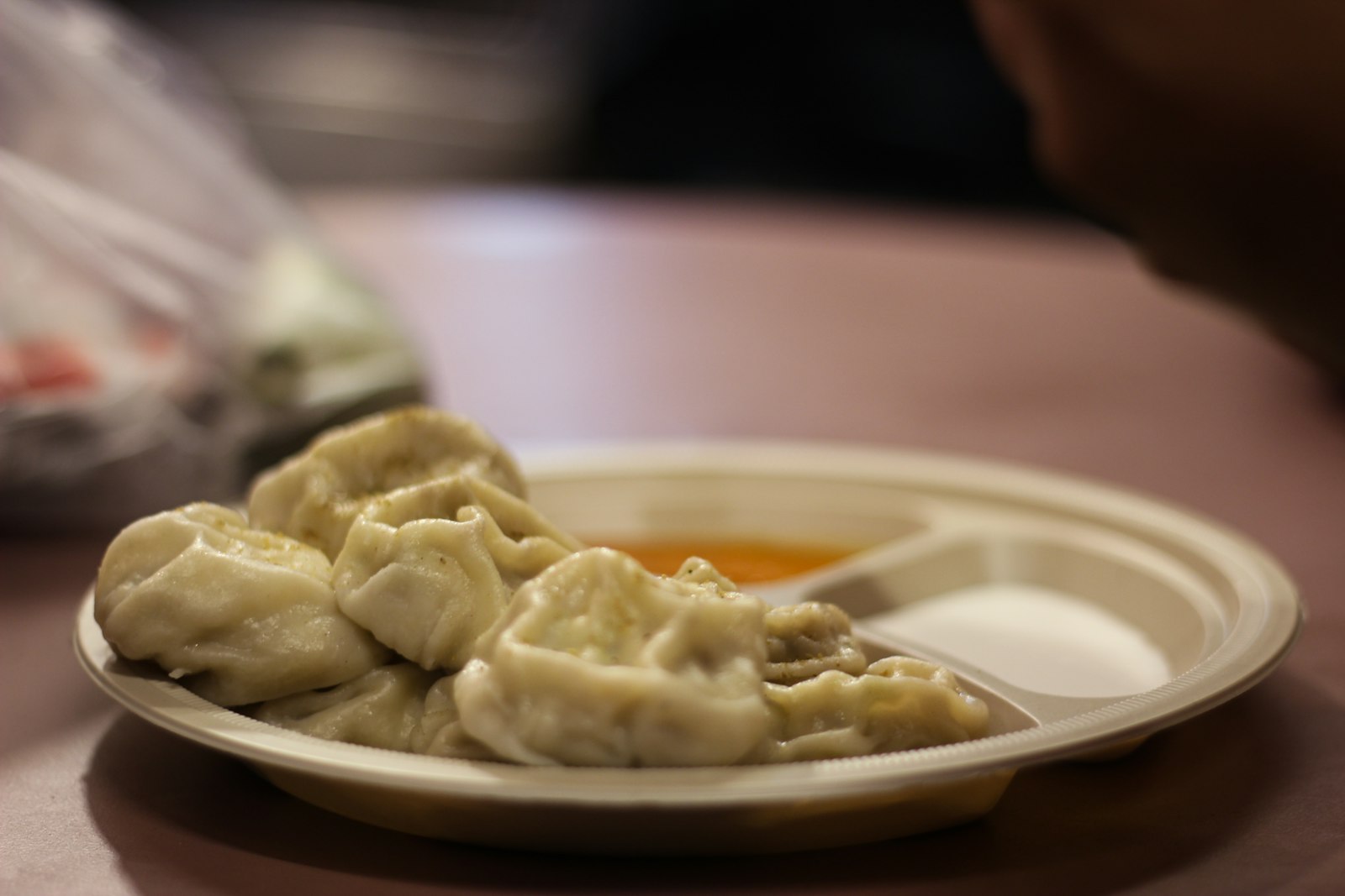 Plate of steamed momos with dipping sauce on a cafe table